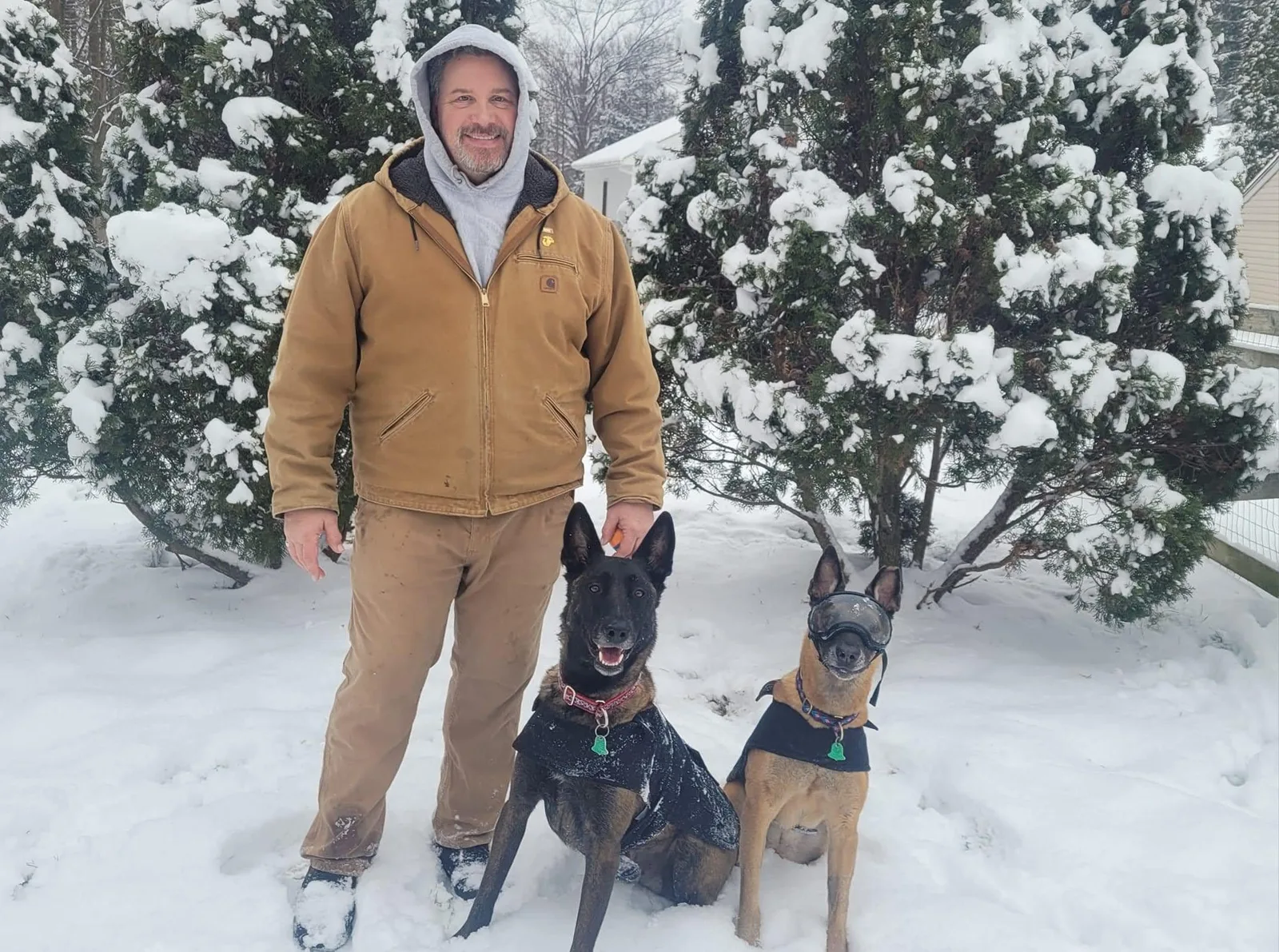 Harvey Betts outdoors in the snow with his two K9 dogs